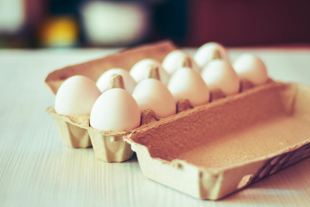 pexels-photo-31992556-31992556 - Chickie-ChickieBees.com A detailed close-up of organic white chicken eggs in a carton, perfect for healthy food themes.